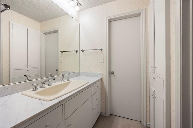 bathroom with a textured ceiling and wallpapered walls