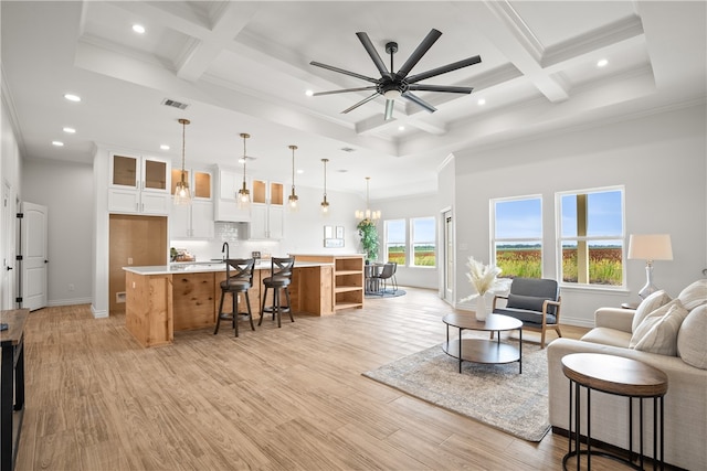 living room featuring light hardwood / wood-style flooring, beam ceiling, crown molding, and coffered ceiling