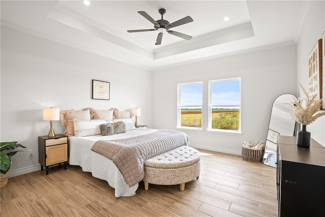 bedroom with ceiling fan, a tray ceiling, light wood-type flooring, and ornamental molding