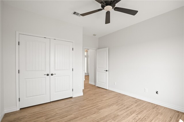 unfurnished bedroom featuring ceiling fan, a closet, and light wood-type flooring