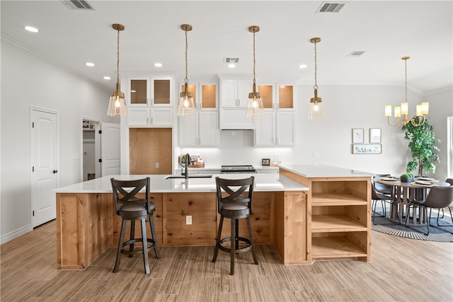 kitchen featuring a large island, white cabinetry, sink, a breakfast bar, and light wood-type flooring