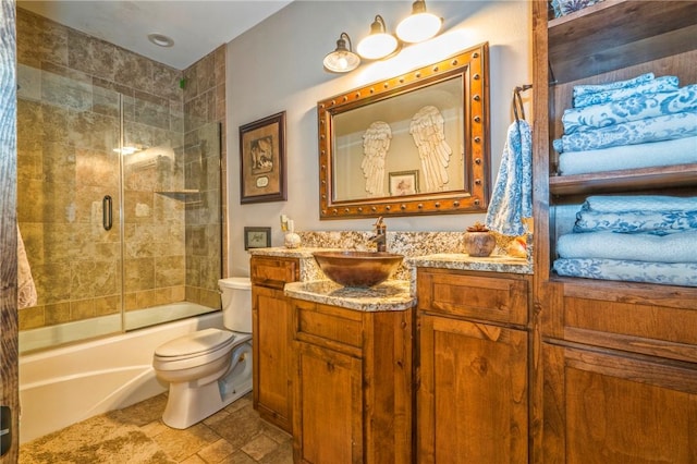 full bathroom featuring vanity, combined bath / shower with glass door, and toilet