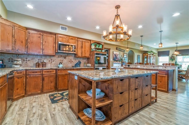 kitchen featuring stainless steel appliances, a center island, light stone countertops, and backsplash