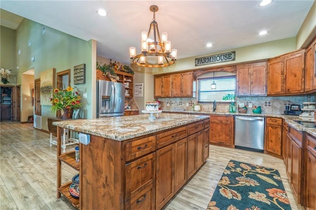 kitchen featuring light stone countertops, stainless steel appliances, a center island, and hanging light fixtures