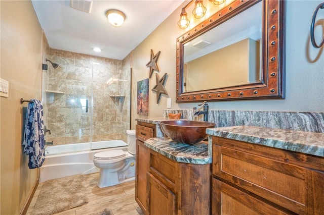 full bathroom with tiled shower / bath combo, vanity, wood-type flooring, and toilet