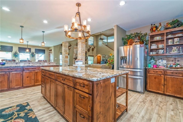 kitchen with pendant lighting, stainless steel fridge with ice dispenser, light wood-type flooring, and a kitchen island