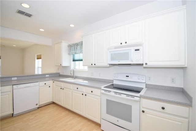 kitchen with white cabinets, white appliances, light hardwood / wood-style floors, and sink