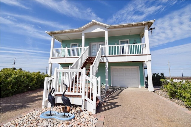 raised beach house featuring covered porch and a garage