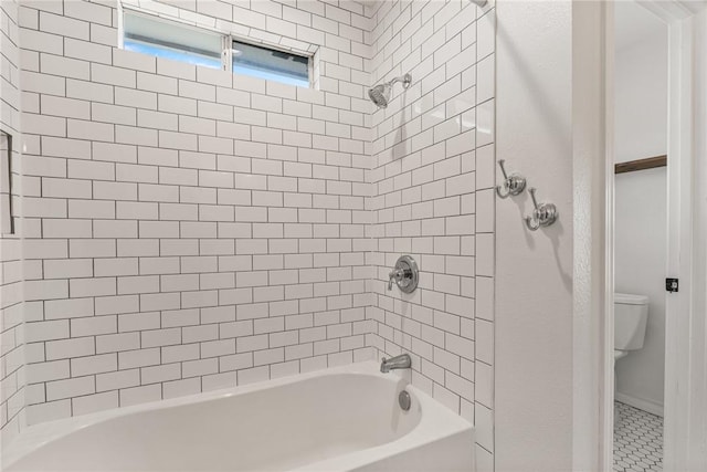 bathroom with toilet and tiled shower / bath combo