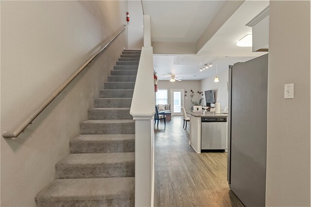 stairway with ceiling fan and wood-type flooring