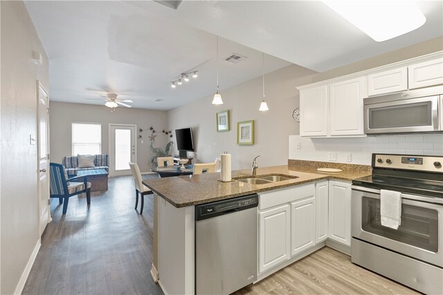 kitchen with white cabinetry, kitchen peninsula, appliances with stainless steel finishes, and sink