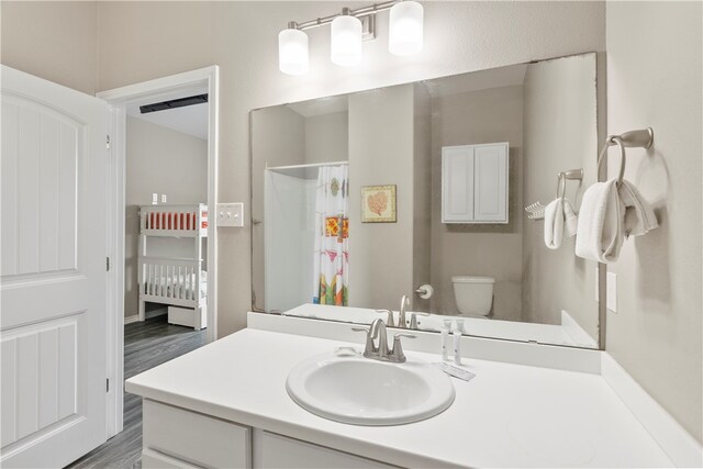 bathroom with toilet, vanity, wood-type flooring, and curtained shower