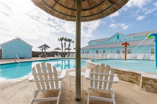 view of pool with an outdoor structure, pool water feature, and a patio