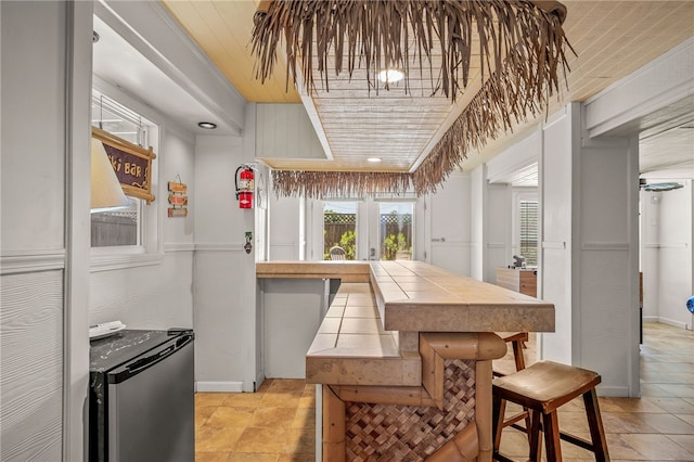 kitchen featuring stainless steel refrigerator, tile countertops, and a breakfast bar