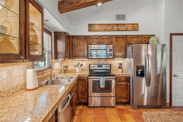 kitchen with sink, light stone counters, lofted ceiling with beams, stainless steel appliances, and decorative backsplash