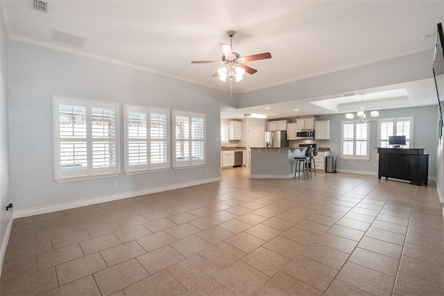 living area featuring light tile patterned flooring, visible vents, baseboards, and ceiling fan with notable chandelier
