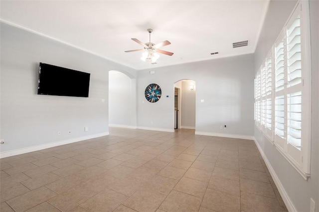 spare room with light tile patterned flooring, visible vents, a ceiling fan, and arched walkways