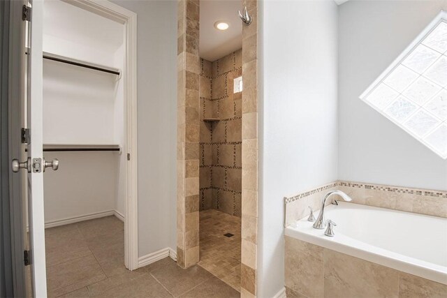 bathroom featuring walk in shower, a walk in closet, a garden tub, and tile patterned flooring