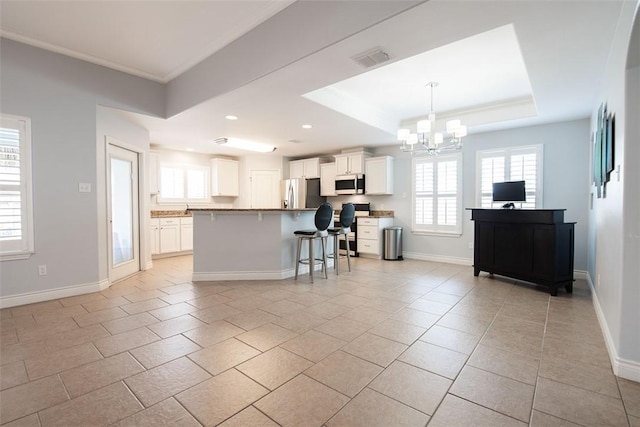 kitchen featuring stainless steel appliances, a kitchen breakfast bar, an inviting chandelier, white cabinets, and baseboards