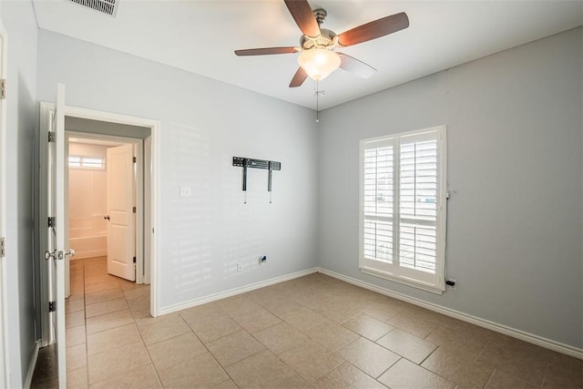 empty room with baseboards, light tile patterned floors, visible vents, and a ceiling fan
