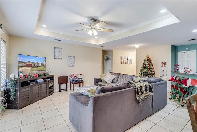 living room with a tray ceiling, ceiling fan, light tile patterned flooring, and ornamental molding