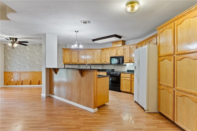 3606 Emory Dr, Corpus Christi, TX 78410 - kitchen with black appliances, dark countertops, a kitchen bar, light wood-type flooring, and wallpapered walls