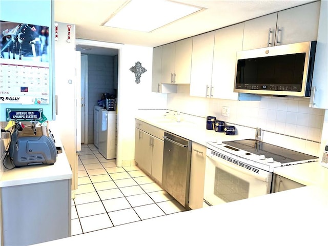 4242 Gulfbreeze Blvd Unit 606, Corpus Christi, TX 78402 - kitchen with appliances with stainless steel finishes, washing machine and dryer, light countertops, light tile patterned floors, and tasteful backsplash