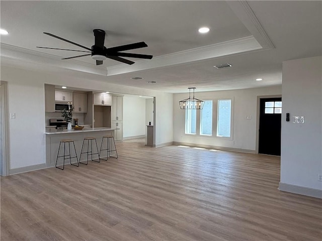 2413 Still Brook Dr, Corpus Christi, TX 78414 - unfurnished living room featuring visible vents, light wood-type flooring, ornamental molding, and a raised ceiling