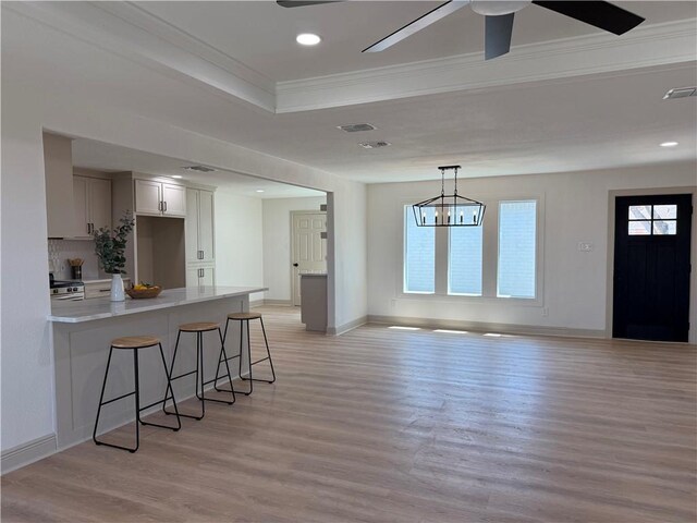 2413 Still Brook Dr, Corpus Christi, TX 78414 - kitchen featuring light countertops, a breakfast bar, a peninsula, ceiling fan with notable chandelier, and light wood-style flooring