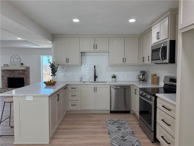 2413 Still Brook Dr, Corpus Christi, TX 78414 - kitchen featuring a fireplace, a kitchen bar, a peninsula, a sink, and stainless steel appliances