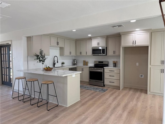 2413 Still Brook Dr, Corpus Christi, TX 78414 - kitchen featuring visible vents, a sink, a peninsula, light wood finished floors, and stainless steel appliances