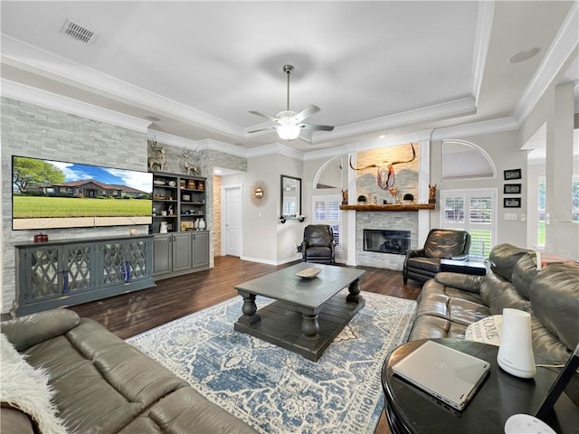 13910 Riverway Dr, Corpus Christi, TX 78410 - living area with a raised ceiling, a stone fireplace, dark wood-style floors, a ceiling fan, and crown molding