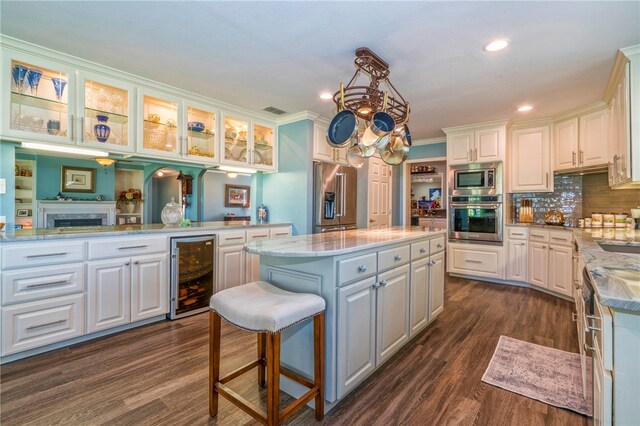 kitchen with stainless steel appliances, white cabinetry, wine cooler, and a center island