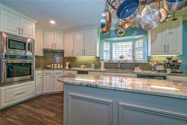 kitchen featuring stainless steel appliances, dark wood-type flooring, white cabinets, sink, and backsplash