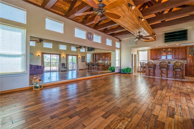 interior space with a towering ceiling, beam ceiling, and indoor bar