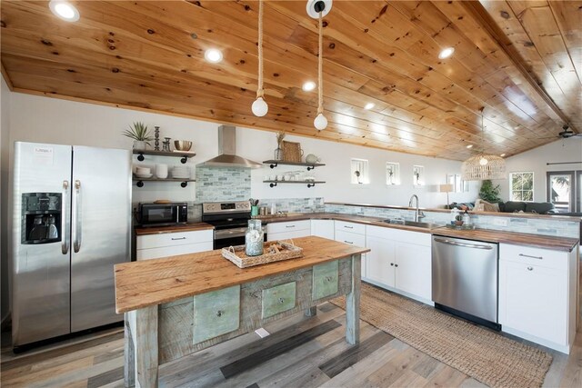 1002 State Highway 361, Port Aransas, TX 78373 - kitchen featuring appliances with stainless steel finishes, wall chimney range hood, a sink, open shelves, and butcher block counters
