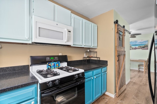 kitchen with white microwave, a barn door, blue cabinets, gas stove, and dark countertops