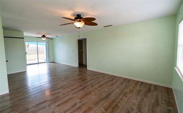 empty room featuring dark wood-style floors, visible vents, and baseboards