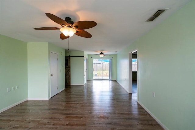 unfurnished room featuring dark wood-style floors, baseboards, visible vents, and a barn door