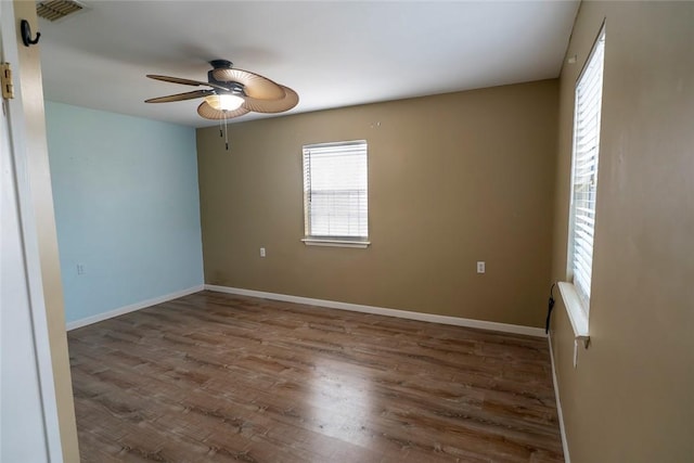 unfurnished room with a ceiling fan, wood finished floors, visible vents, and baseboards