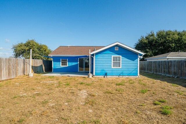 rear view of house with a patio area, a fenced backyard, and a yard