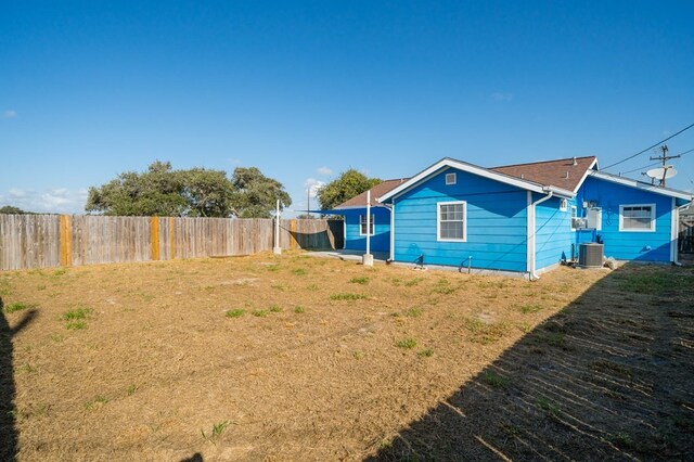 exterior space with a fenced backyard, a lawn, and central AC unit