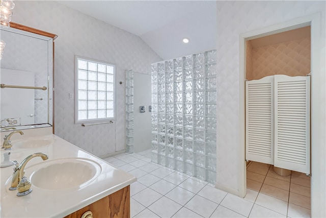 bathroom with vanity, tile patterned flooring, a tile shower, and lofted ceiling