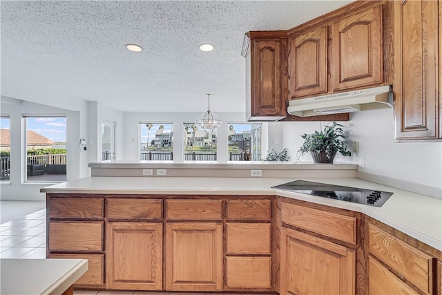 13714 A La Entrada St, Corpus Christi, TX 78418 - kitchen with under cabinet range hood, black electric cooktop, a textured ceiling, light countertops, and a peninsula