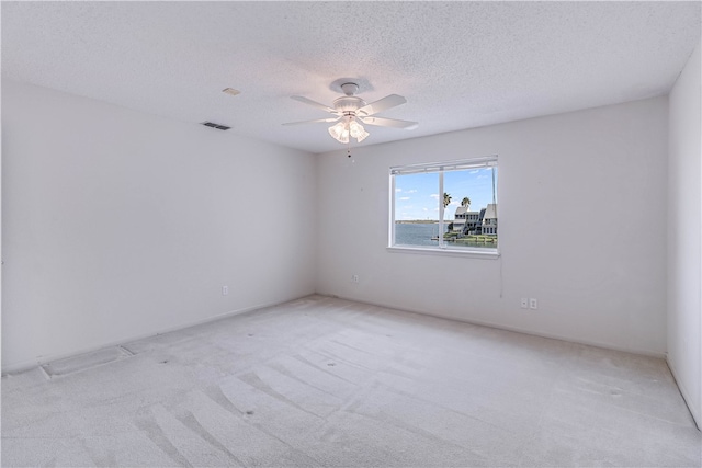 empty room featuring light colored carpet, a textured ceiling, and ceiling fan