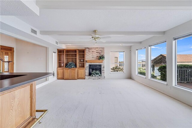 13714 A La Entrada St, Corpus Christi, TX 78418 - unfurnished living room featuring beam ceiling, carpet flooring, a fireplace, ceiling fan, and baseboards