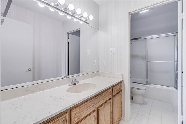 full bathroom featuring toilet, combined bath / shower with glass door, vanity, and tile patterned flooring