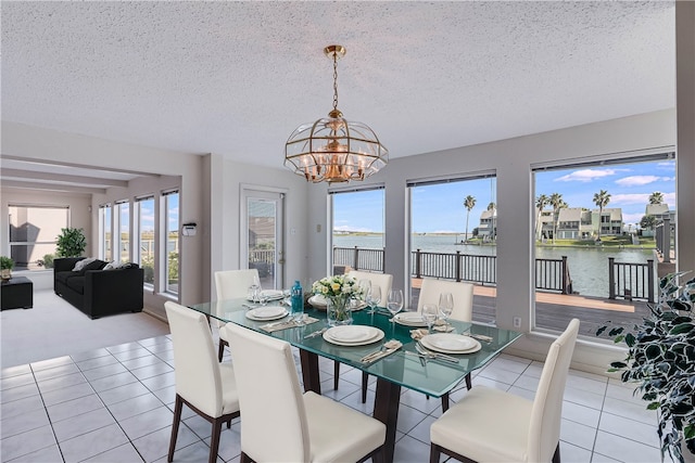 dining area with a chandelier, a healthy amount of sunlight, a water view, and a textured ceiling