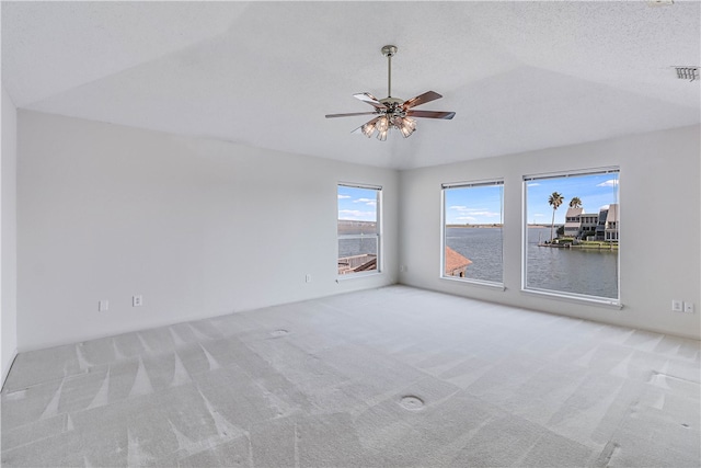 carpeted spare room featuring a textured ceiling, a water view, and ceiling fan