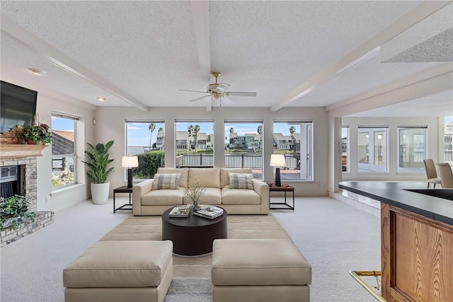 13714 A La Entrada St, Corpus Christi, TX 78418 - living room featuring carpet floors, beamed ceiling, a textured ceiling, ceiling fan, and a fireplace with raised hearth